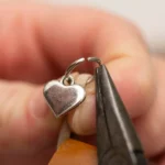 Relicário de cinzas personalizado em formato de colar, com acabamento em prata, sobre superfície de madeira clara