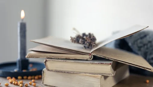 Uma pessoa sentada confortavelmente segurando um livro aberto, com uma xícara de chá ao lado, transmitindo um momento de paz e reflexão.