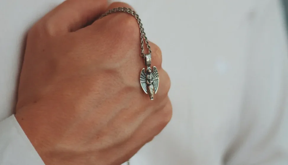 Mãos segurando um pingente delicado com uma foto, simbolizando joias afetivas e presentes de conforto para mães em luto.
